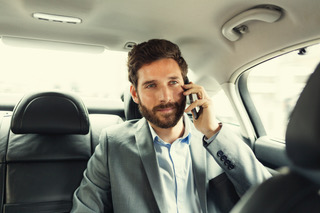 Casual business man on mobile phone in rear of car